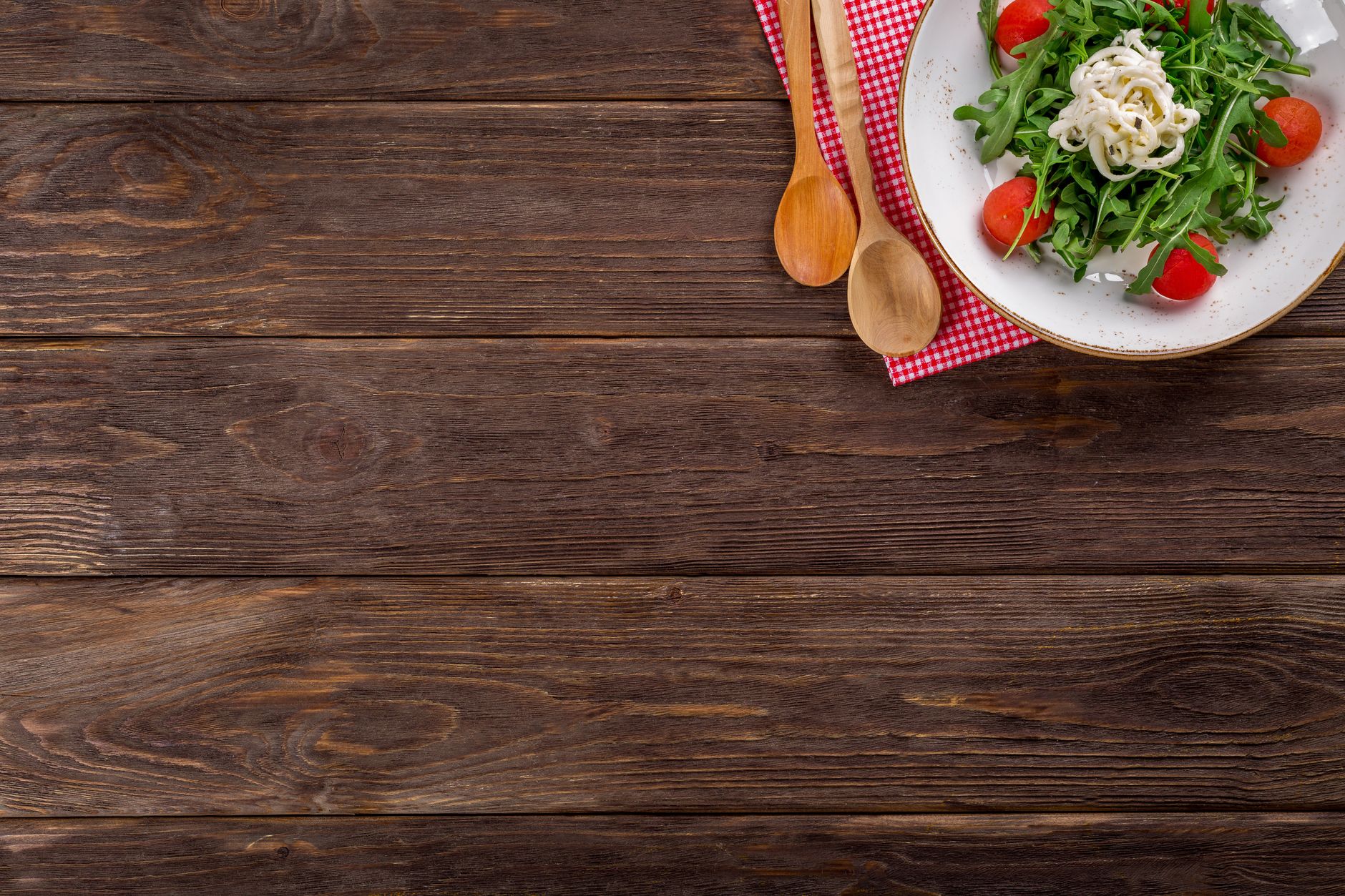 A delicious arugula salad with cherry tomatoes and pasta served on a rustic wooden table with space for text.